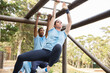 © Sam Edwards/KOTO - Determined woman swinging on monkey bars on boot camp obstacle course
