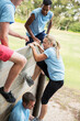 © Sam Edwards/KOTO - Teammates helping woman over wall on boot camp obstacle course