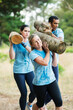 © Sam Edwards/KOTO - Determined woman running with log on boot camp obstacle course