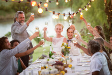 Young Couple Their Guests Toasting Champagne During Wedding Reception In Garden