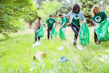 environmentalist volunteers picking up trash in field