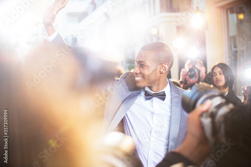 Fotografía Smiling celebrity waving to paparazzi photographers at event
