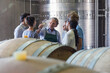 Vintner and winery employees examining wine in cellar