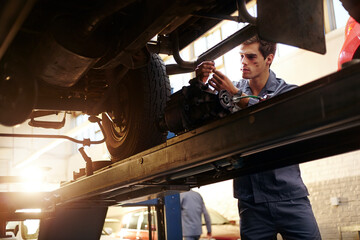 Wall Mural - Mechanic working under car in auto repair shop