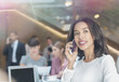 © Tom Merton/KOTO - Businesswoman talking on cell phone in office