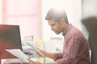 Focused businessman digital tablet reviewing paperwork at desk in office