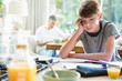 © Chris Ryan/KOTO - Frustrated boy doing homework at breakfast