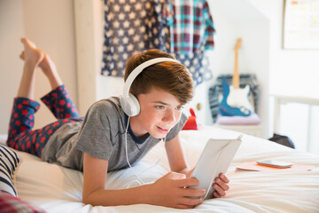 Boy with headphones listening to music on digital tablet