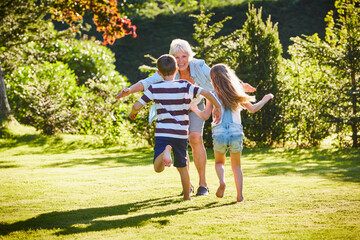 Grandchildren running to grandmother in sunny garden