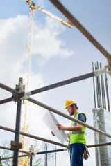 Engineer reviewing blueprints at high rise construction site