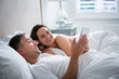 © Chris Ryan/KOTO - Smiling couple laying in bed using digital tablet