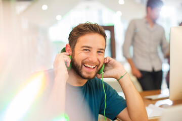 Wall Mural - Portrait enthusiastic creative businessman listening to headphones in office