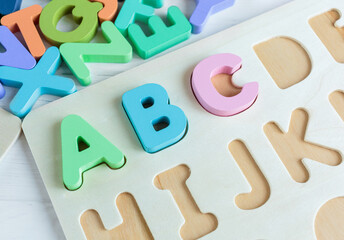 Wall Mural - Close up Multicolored wooden letters with ABC on white wooden background. Set of toys for studying alphabet. Education, back to school concept. Top view, copy space