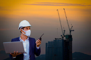 Portrait engineer under working and checking process on construction building site by laptop computer and radio communication wearing face mask protect virus and pollution.