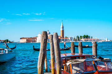 Gondolas and motorboats moored by Saint Mark square with San Giorgio di Maggiore church in the background in Venice, Italy. Architecture and landmarks of Venice.