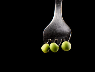 Ripe peas are strung on cloves of a fork.