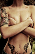 Mujer tatuada tapando pechos