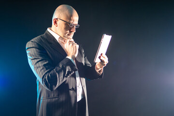 Poster - Getting information using an electronic tablet. A man in a black suit looks at information on a tablet computer. Portable computer for getting data anywhere.