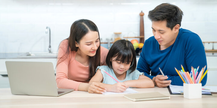 Fototapete - Father and mother teaching children to do their homework at home. Happy asian family using the laptop together at home. Young asian family parents helping daughter drawing at home