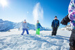 Group of happy children play snowball fight throwing snow over mountains peaks in fun game