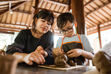 mother and her son try to make clay handicrafts in the pottery workshop gallery