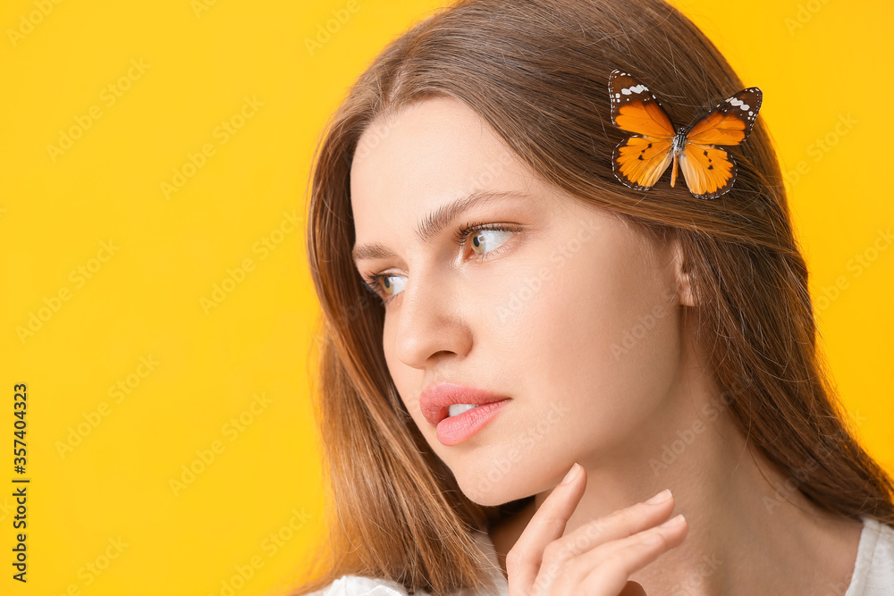 Beautiful young woman with butterfly on color background