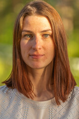 Portrait of a young red-haired girl, Girl looking at the camera and smiling shyly. Freckles on the face