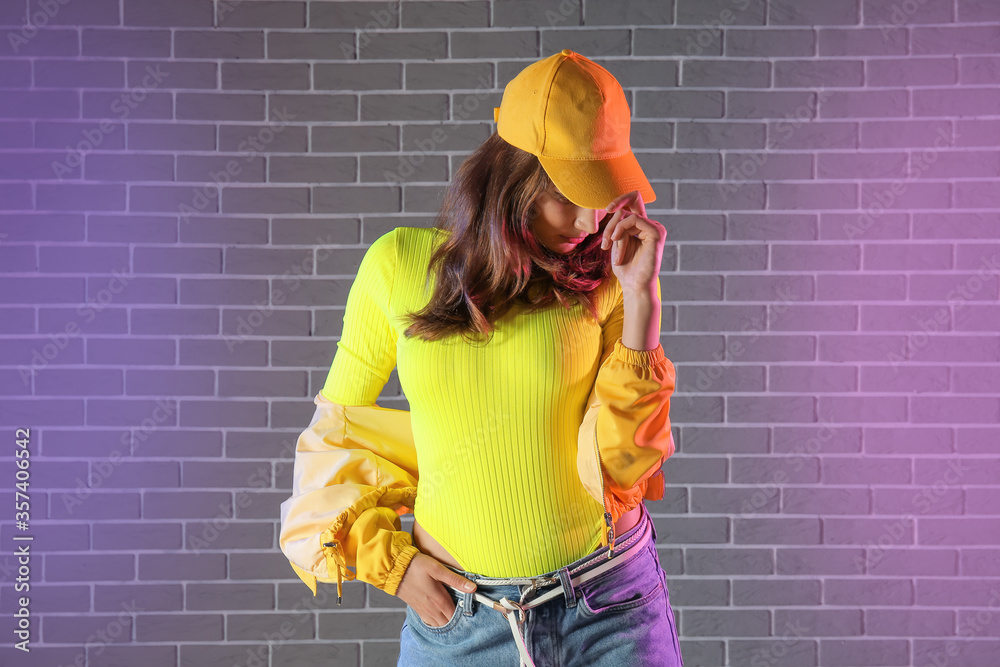 Beautiful female hip-hop dancer against brick wall