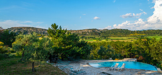 Private outdoor luxury swimming pool overlooking the beautiful mountain views. Holiday, relax, vacantion. Lovely pool in the garden area, surrounded by plants. Auvergne ‐ Rhone ‐ Alpes, France.