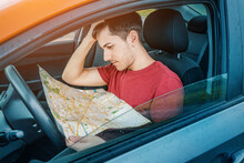 A Frustrated Man Gets Lost And Tries To Find His Location On A Map While Sitting In A Car