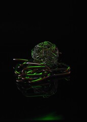 Sticker - Vertical shot of chains and a metal ball in with a dark background and a green light shining on them