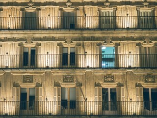 Canvas Print - Old building with windows and beautiful carvings at night time