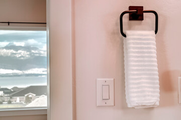 Wall Mural - White towel hanging on square towel holder beside electrical rocker light switch