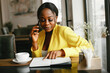 © prostooleh - Elegant black woman. Lady in a yellow jacket. Businesswoman working in a office