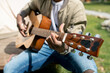 © pressmaster - Close-up of unrecognizable musician playing acoustic guitar outdoors while enjoying camping