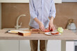 © Evgenia - A boy in a blue shirt is preparing a sandwich of vegetables, meat and bread.