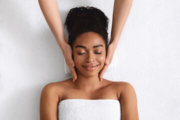 top view of relaxed black woman having facial massage