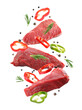 Raw beef meat and other ingredients falling on white background