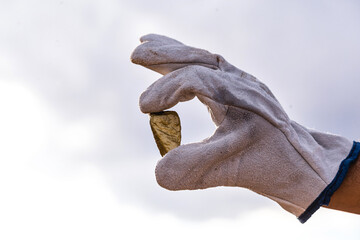 gold stone close-up in the hand of a mining company with glove. Mining exploration concept.