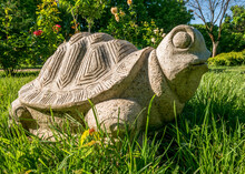 Figurine Turtle Made Of Stone Sitting On Green Grass.