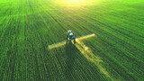 Fototapeta  - Tractor spray fertilizer on green field drone high angle view, agriculture background concept.