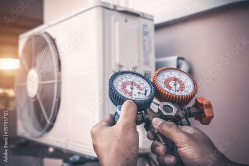 Cuadros en Lienzo Air repair mechanic using measuring pressure gauge equipment for filling home air conditioner after cleaners and checking maintenance outdoor air compressor unit
