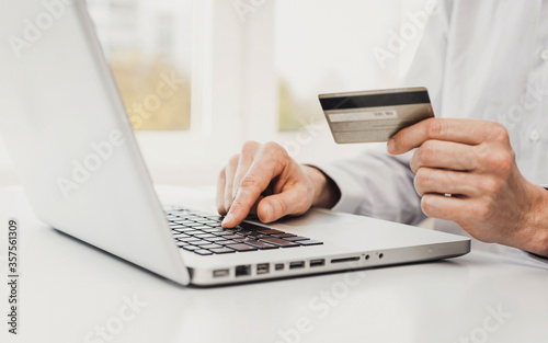 Man hand holding credit card and using laptop at home, Businessman or entrepreneur working, Online shopping, e-commerce, internet banking, spending money, working from home concept