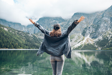 young pretty woman enjoying the view of lake in mountains