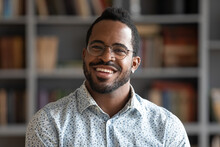 Head Shot Of African American Bearded Guy With Pierced Ear Casual Shirt Smiling Looking At Camera Standing Indoor. Webcam View, Conference Video Call, Confident Company Representative Portrait Concept
