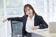 © FILEOPEN CREATION - Beautiful Asian businessman wearing a black suit sitting in the office, smiling confidently and looking at the camera.
