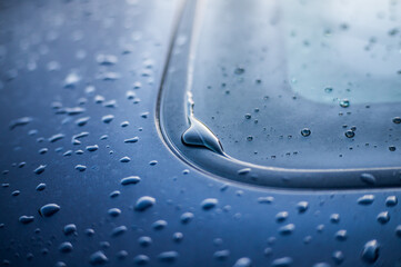 Raindrops on a blue car close-up.