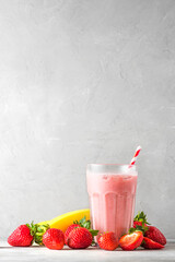 Wall Mural - Strawberry and banana smoothie or milkshake in a glass with a straw with fresh fruits. refreshing summer drink