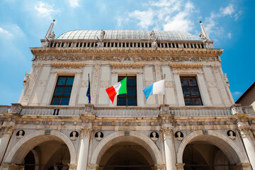 Comune di Brescia - City or town hall of Brescia, Lombardy, Italy. The main Italian landmark with a round roof, white walls, windows, sculptures, flags of European Union. Architecture. Heritage.