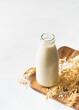 © Denira - Oat milk in glass bottle with flakes and spike or ears of grain on white background